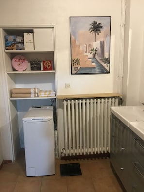 Et lille køkken med indbygget vaskemaskine, radiator og vask.