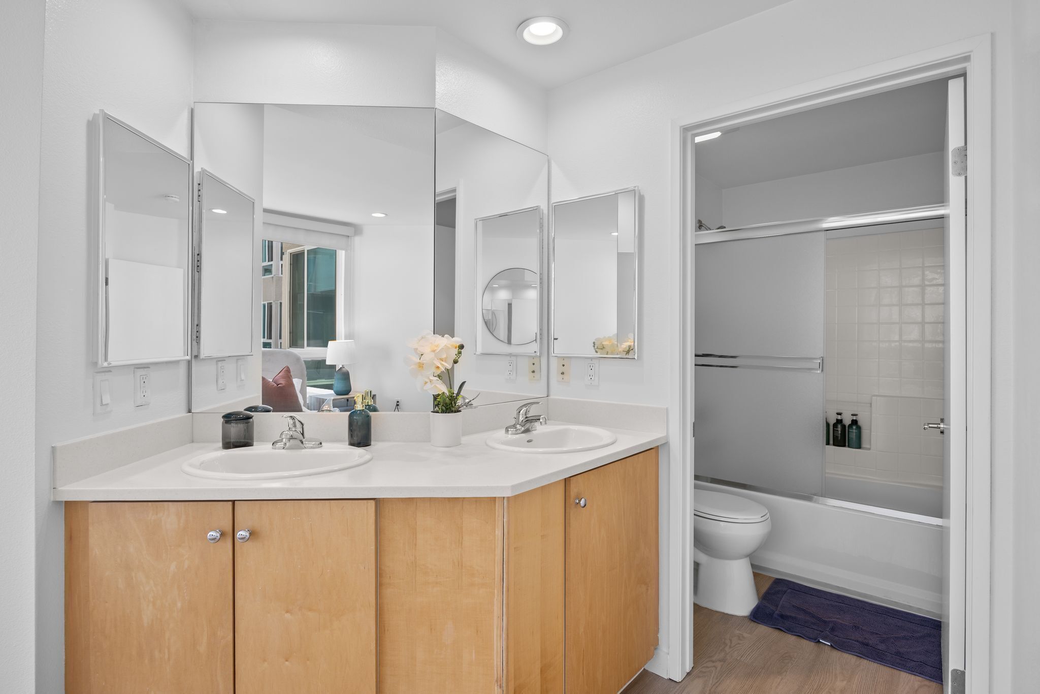A modern bathroom with two sinks, a toilet, a shower, and a large mirror.