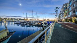 A marina with boats docked, a waterfront promenade, and a modern building with balconies. - The Grace Bay' Private Rooftop Penthouse Water Views Retreat Pool Sauna and Gym (Marina del Rey)