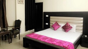 Ein Hotelzimmer mit einem Bett, einem Sessel, einem Schreibtisch und einem schwarzen Vorhang.