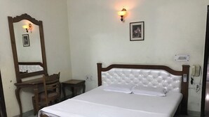 Ein Schlafzimmer mit einem hölzernen Bett, einer Holzkommode, einem Stuhl, einem Nachttisch und einer Wandleuchte.