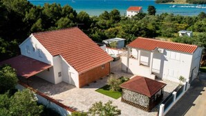 A coastal property with a red-tiled roof, white walls, and a view of the sea. - Four Bedroom Villa With Hot Tub (Pasman)