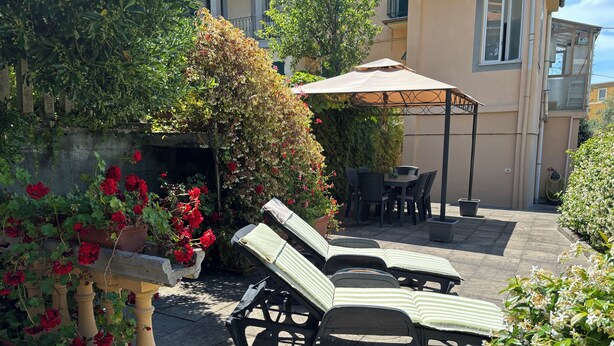 En terrasse med loungesæde, et bord og en parasol.