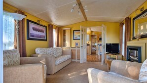 A spacious living room with a sofa set, a television, and a fireplace. - Holiday Home by UK Coast with Sea Views (Great Thorness)