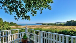 A deck with a white railing overlooking a coastal landscape. - Holiday Home by UK Coast with Sea Views (Great Thorness)