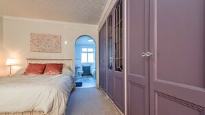 A bedroom with a large bed, a nightstand, a lamp, and a wardrobe.