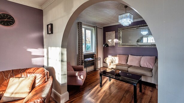 A living room with a leather sofa, a coffee table, and a chandelier.