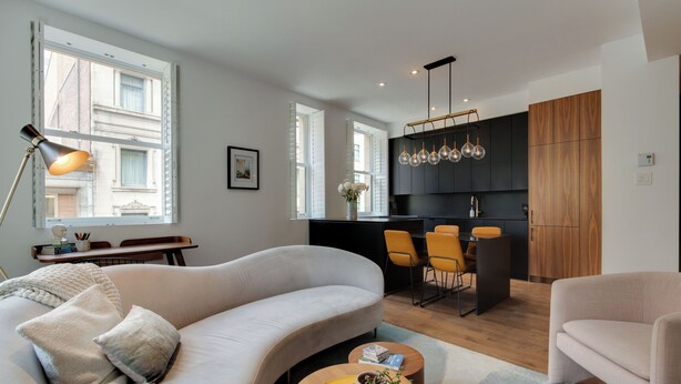 A modern living room with a sofa, coffee table, and a dining area with chairs. - Luxury two bedroom corner unit - Old Montreal - Parking Included (Montréal)