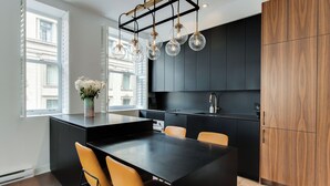 A modern kitchen with a central island, black cabinetry, and a wooden cabinet to the right. - Luxury two bedroom corner unit - Old Montreal - Parking Included (Montréal)