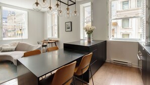 A modern kitchen with a large island, pendant lighting, and large windows offering city views. - Luxury two bedroom corner unit - Old Montreal - Parking Included (Montréal)