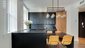 A modern kitchen with a central island, black cabinets, and yellow chairs. - Luxury two bedroom corner unit - Old Montreal - Parking Included (Montréal)