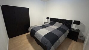 A bedroom with a bed, two bedside tables, a wardrobe, and a nightstand.