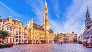 A historic square with a prominent Gothic-style building featuring a tall spire, surrounded by ornate architecture.