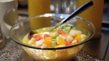 A bowl of fruit salad with a spoon, placed on a textured surface.
