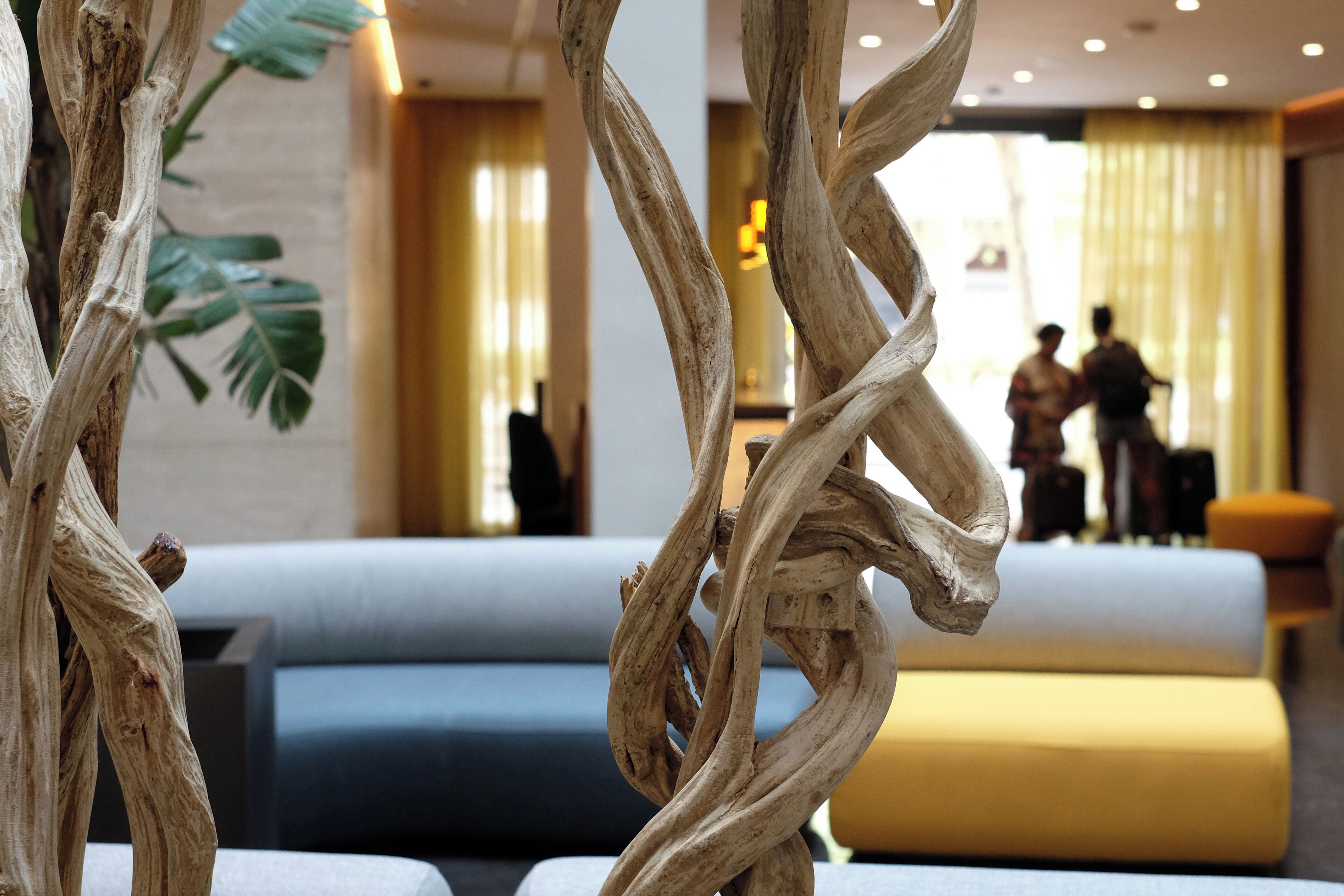 Een moderne lobby met een zithoek, een houten sculptuur en uitzicht op de receptie.