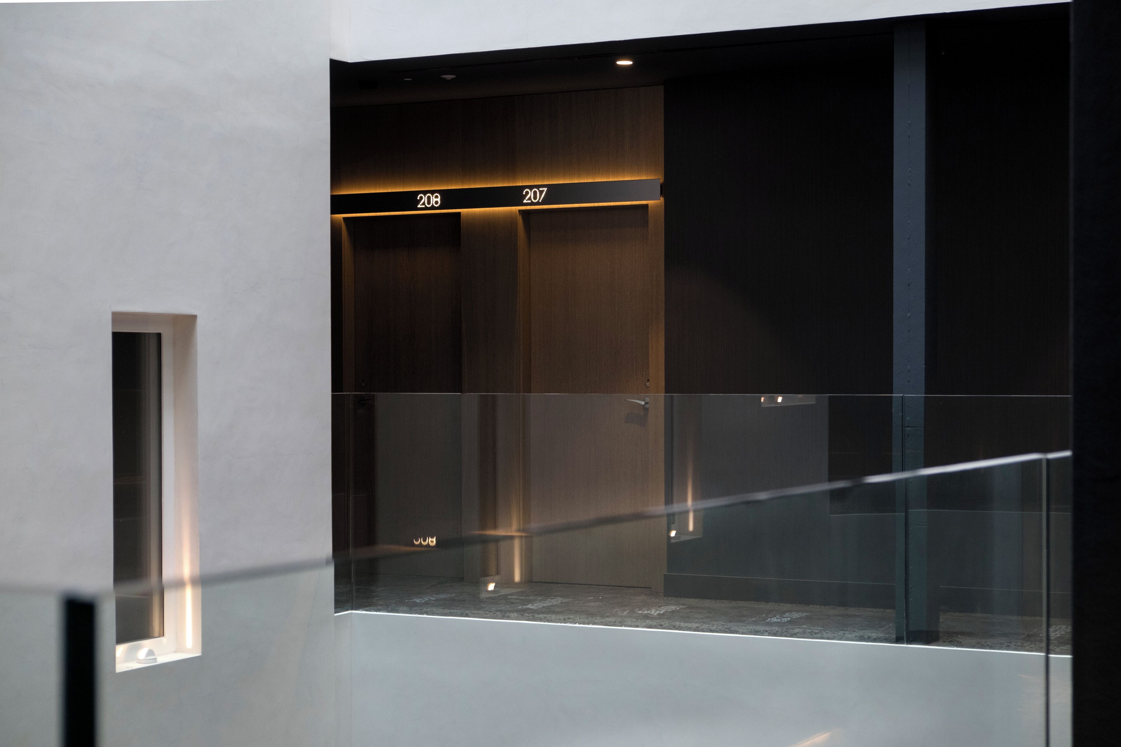 Un ascensore moderno con porte in vetro e un design minimalista, con i numeri 206 e 207 ben visibili.
