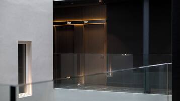 Un ascensore moderno con porte in vetro e un design minimalista, con i numeri 206 e 207 ben visibili.