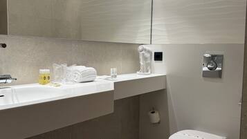 Uma casa de banho moderna com lavatório branco, secador de cabelo, artigos de higiene e sanita.