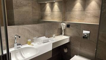 A modern bathroom with a white sink, a hairdryer, and a toilet.