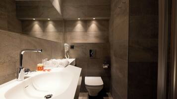 A modern bathroom with a large sink, a toilet, and a shower area.