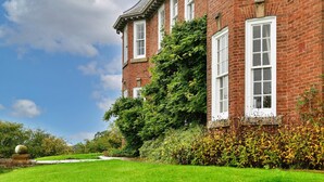 Un edificio in mattoni con finestre bianche e un giardino curato.