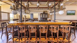 Eine Bar mit Holzsesseln, einer Theke und einer Kristallleuchtre.