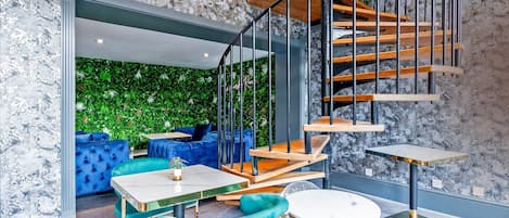 A modern interior with a staircase, seating area, and a green wall.