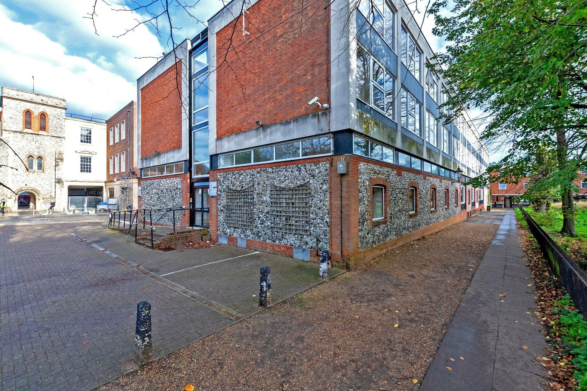 Ein Gebäude mit Ziegelaußenwand, großen Fenstern und einem gepflasterten Gehweg.