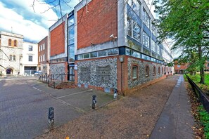 Un edificio con fachada de ladrillo, amplias ventanas y una acera pavimentada.
