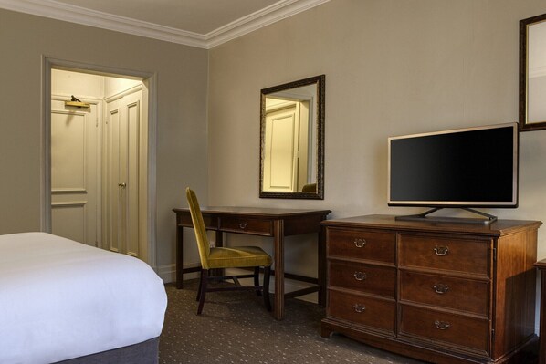 A hotel room with a bed, a desk with a chair, a dresser, a television, and a mirror. - Winchester Wessex Hotel by Sunday Twin Room (Winchester)