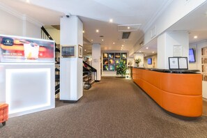Zona de recepción de hotel con mostrador, escalera y un árbol de Navidad.