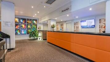 A reception area with a Christmas tree, a reception desk, and a wall with colorful stained glass windows.