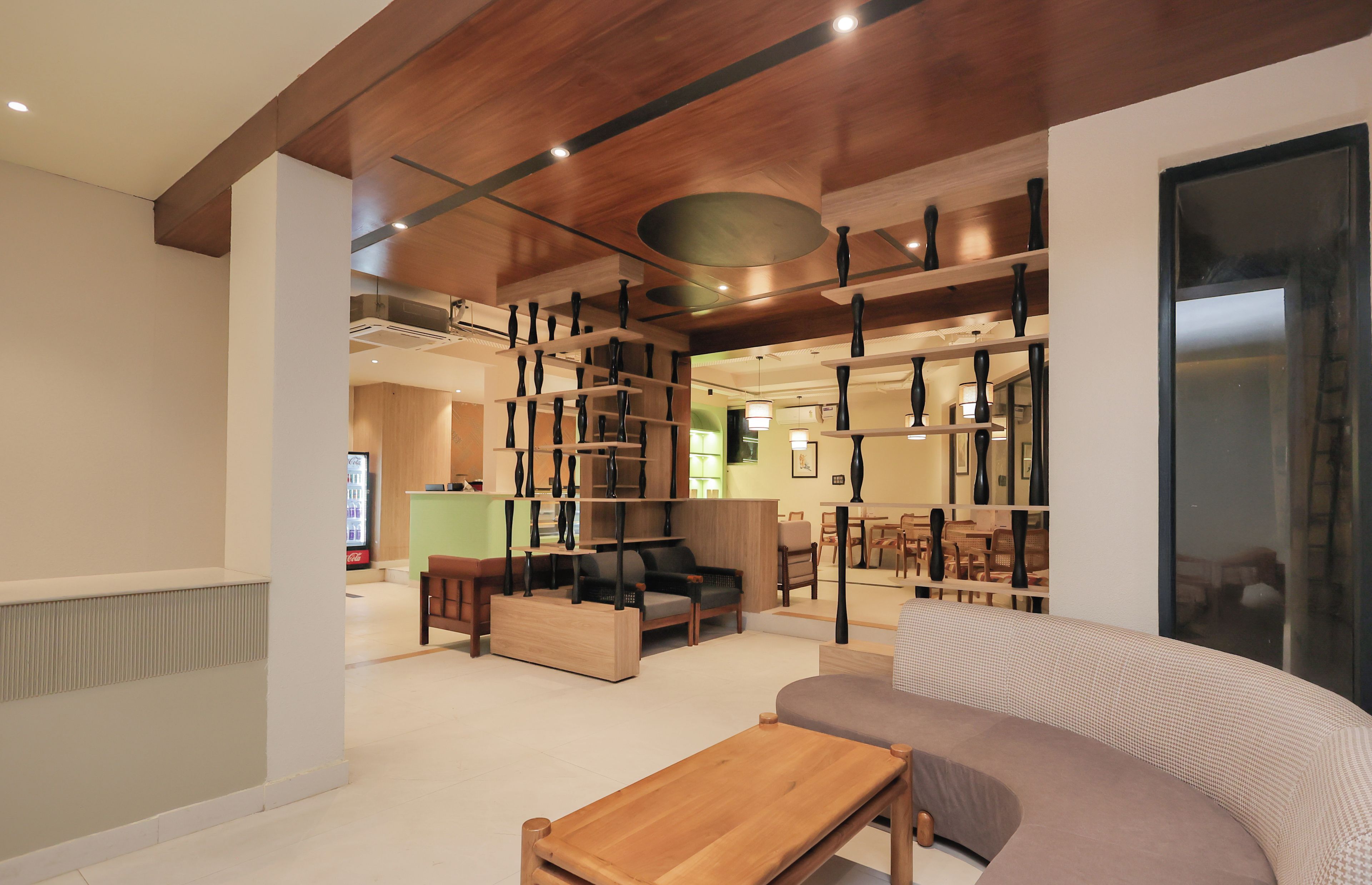 A modern interior with a wooden ceiling, a sofa, a coffee table, and a dining area with chairs and a table.