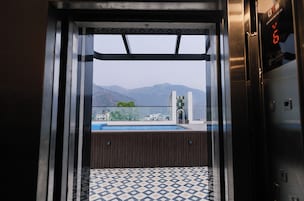 Un ascensor con vistas a una piscina y montañas al fondo.