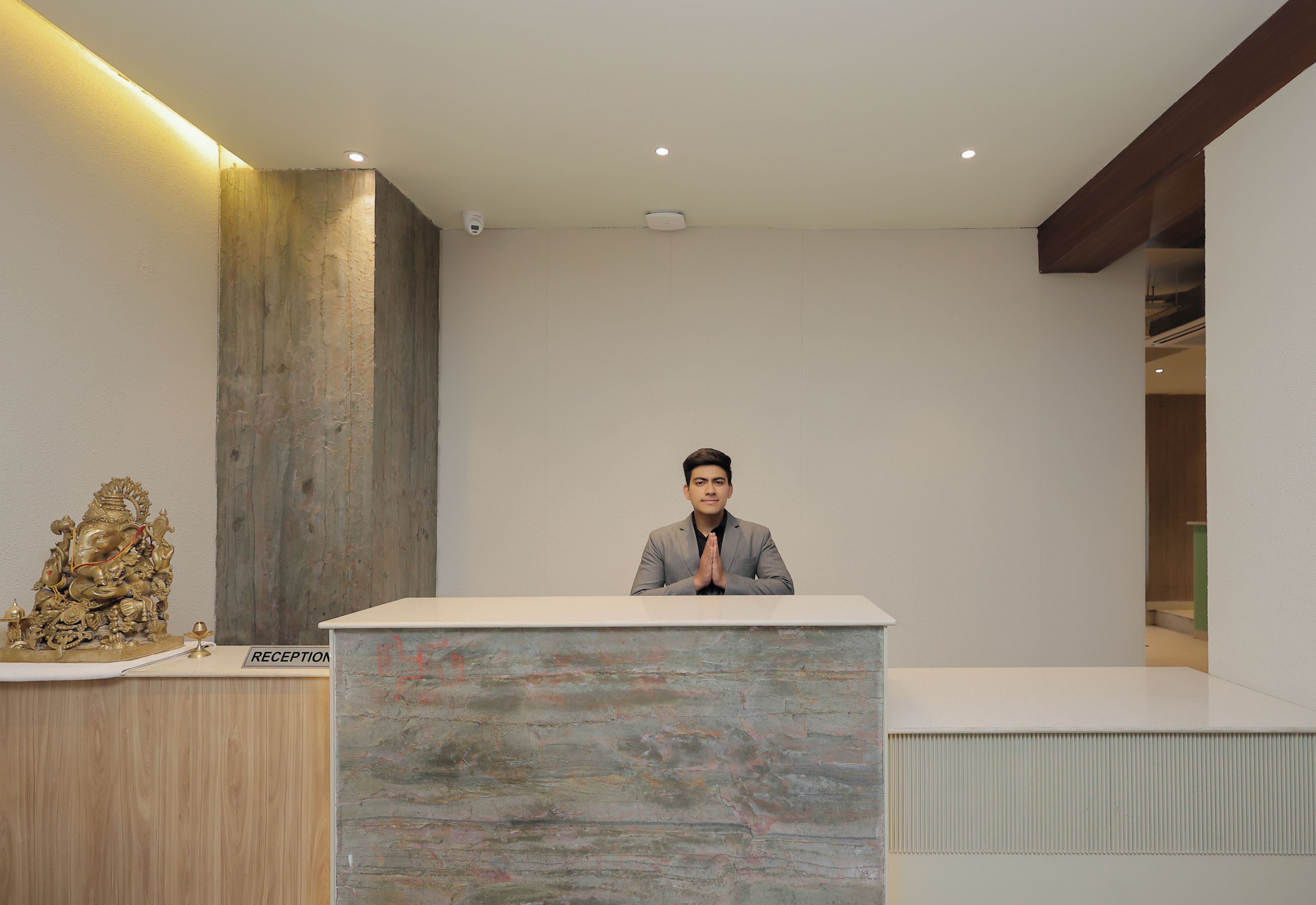 A reception desk with a person standing behind it, a statue on the left, and a 'RECEPTION' sign.