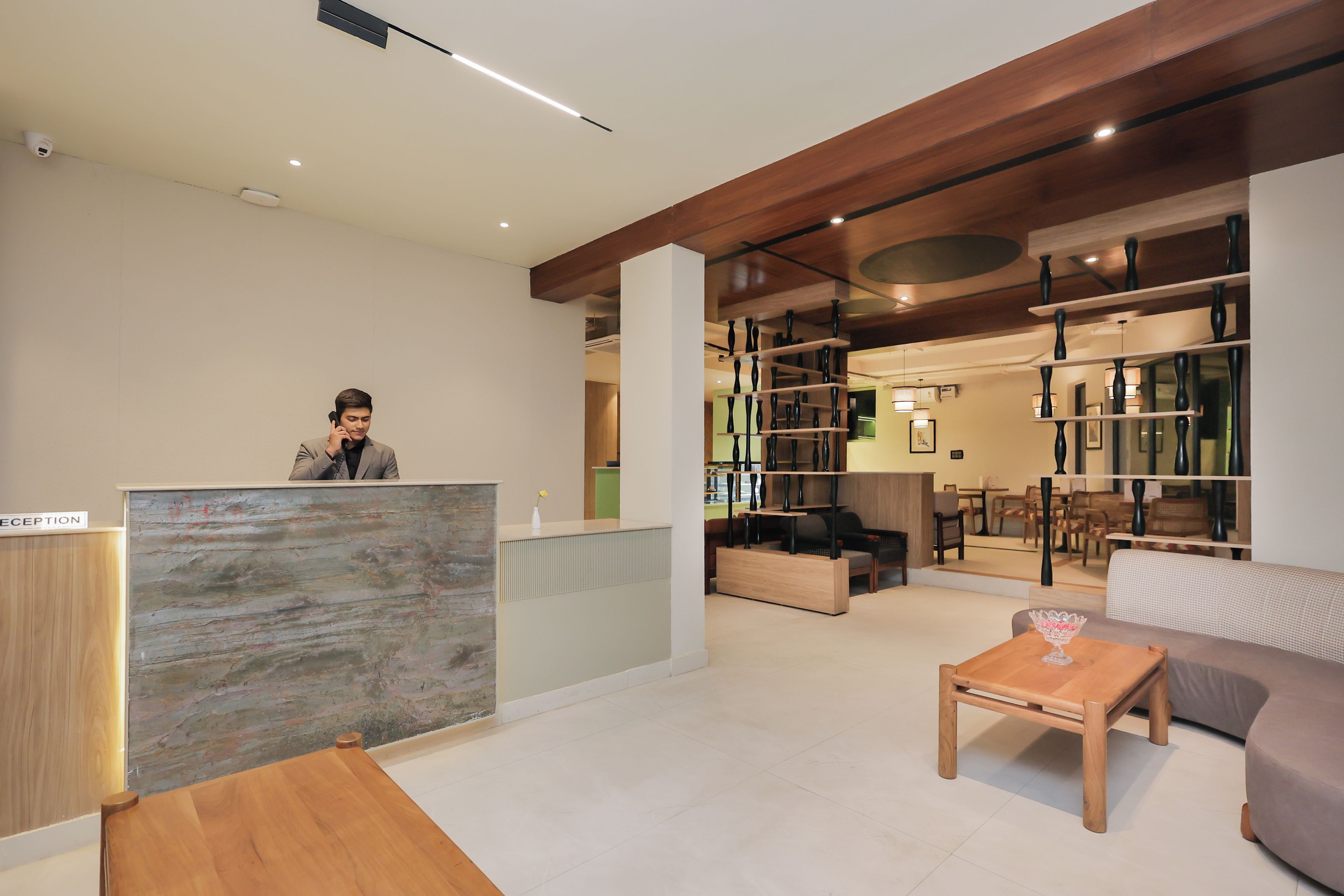 Un espace d’accueil comprenant un comptoir de réception, un espace d’attente avec un canapé et une table basse, ainsi qu’une bibliothèque remplie d’objets décoratifs.
