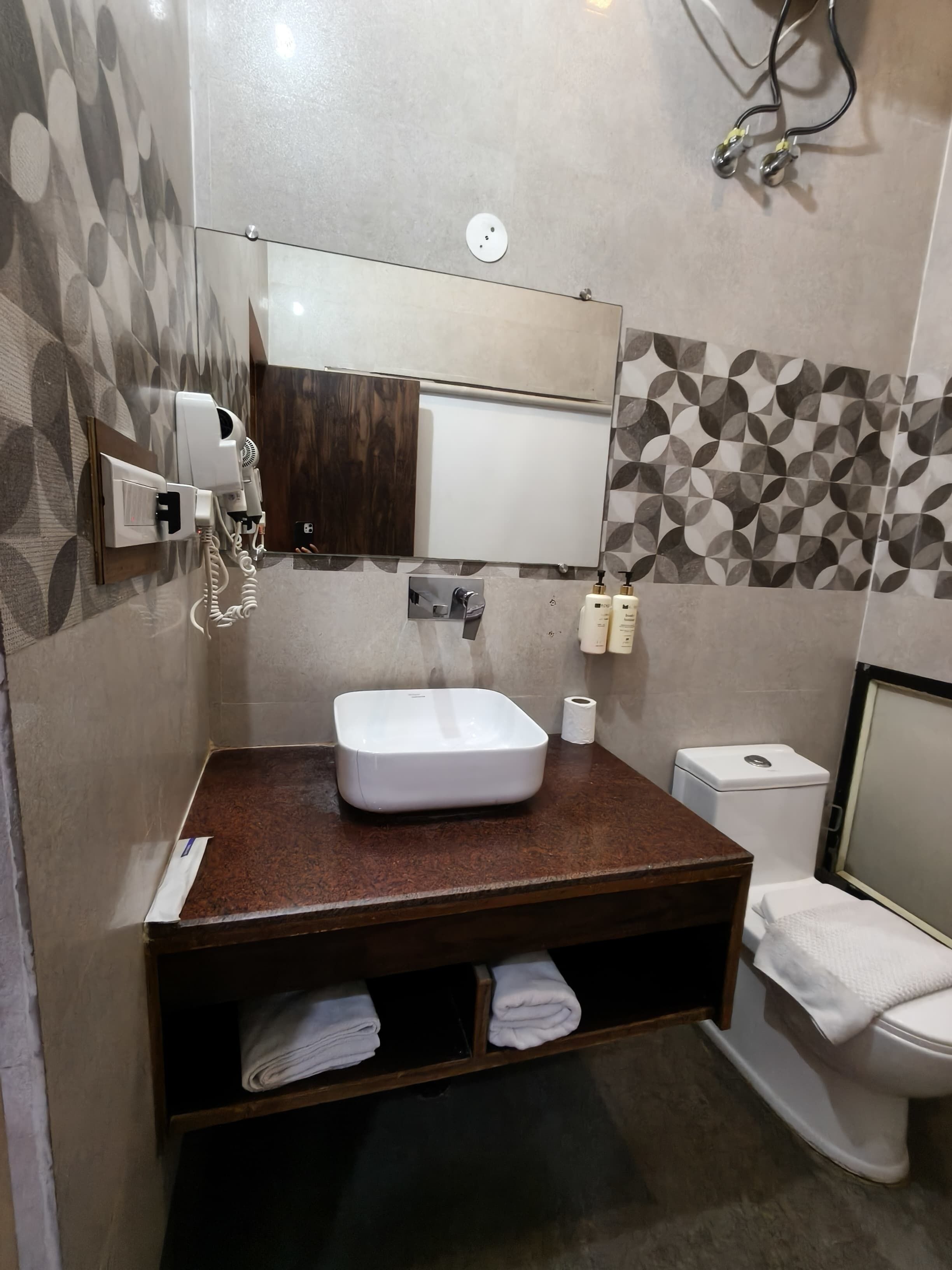 A bathroom with a white sink, a mirror, a hairdryer, and a toilet.