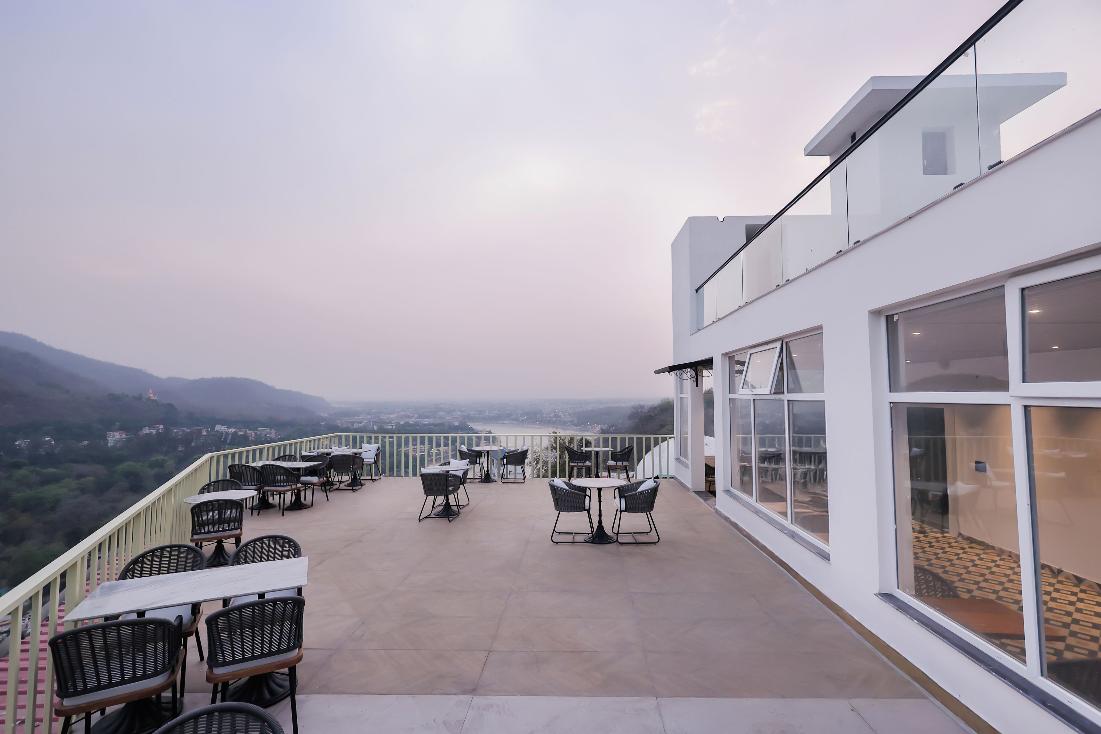 Terraza en la azotea con mesas y sillas, con vistas al paisaje circundante.