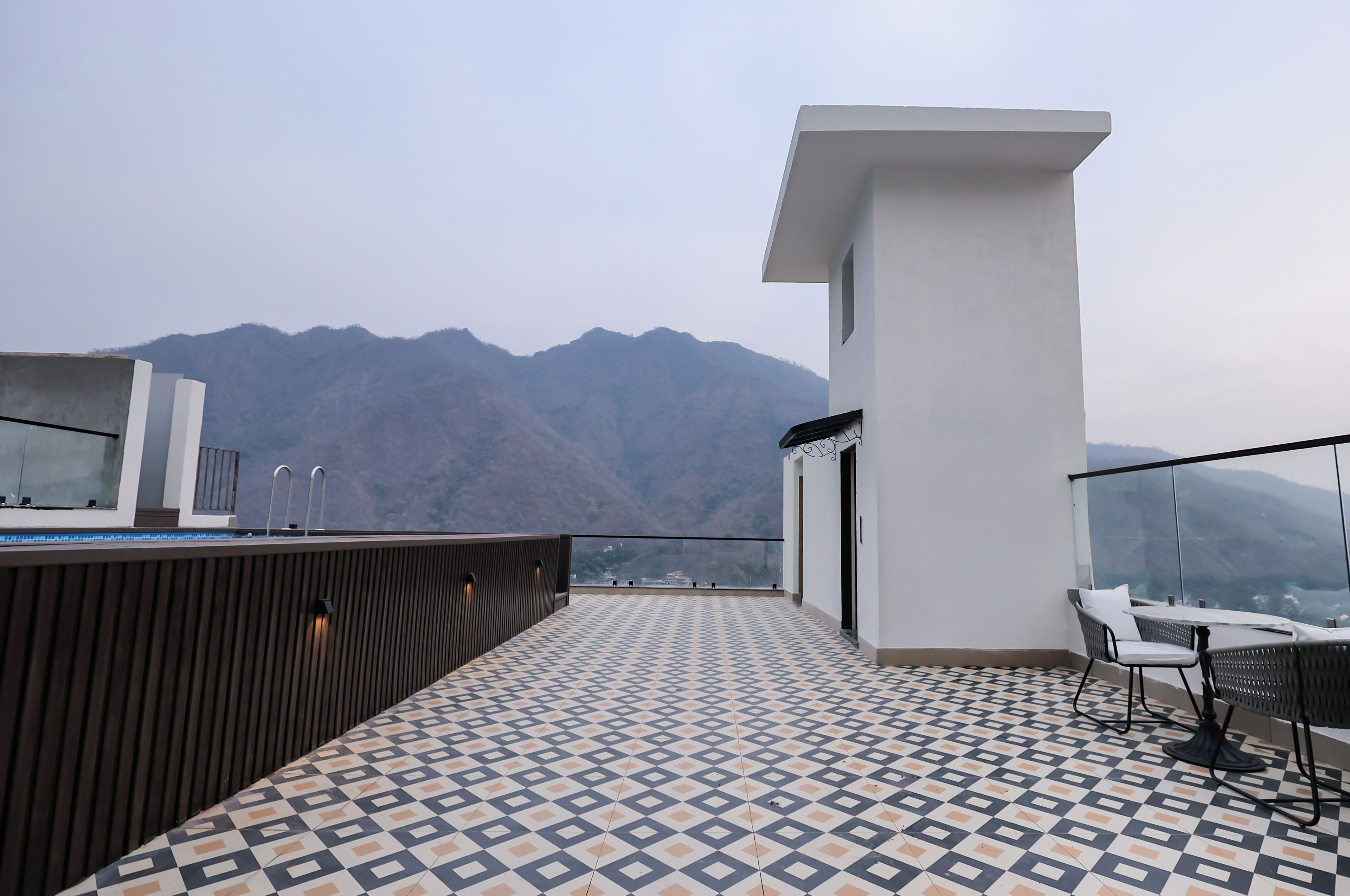 Una terraza en la azotea con suelo estampado, un espacio de estar y vistas a montañas.