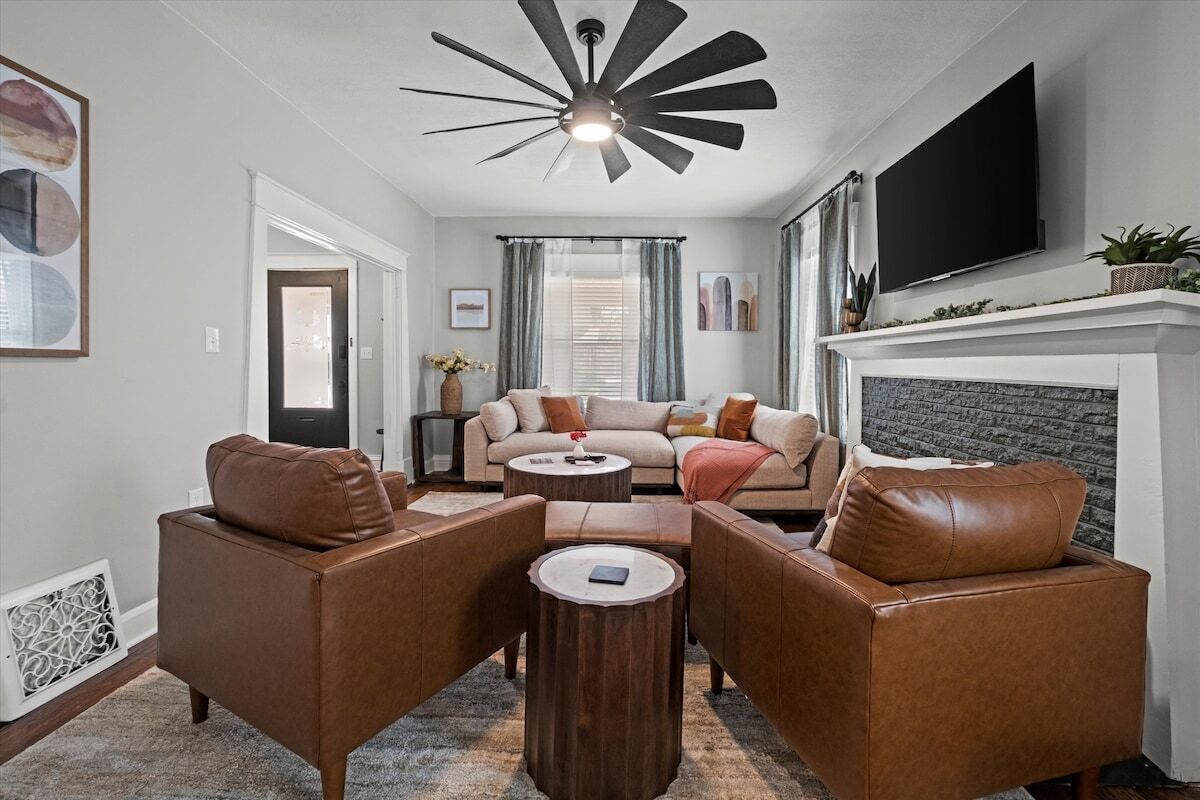 A living room with a fireplace, leather sofas, a coffee table, and a flat-screen TV.