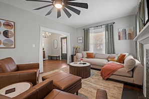 A living room with a sofa, armchairs, a coffee table, and a fireplace. - Heights Hyde Park 2BR Home Near Nelson + Parking (Kansas City)