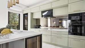 A modern kitchen with light green cabinets, a white countertop, and stainless steel appliances. - Three-Bedroom Penthouse Apartment (Omis)