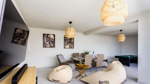 A modern living room with a pool table, bean bags, and a dining area with a table and chairs. - Three-Bedroom Penthouse Apartment (Omis)