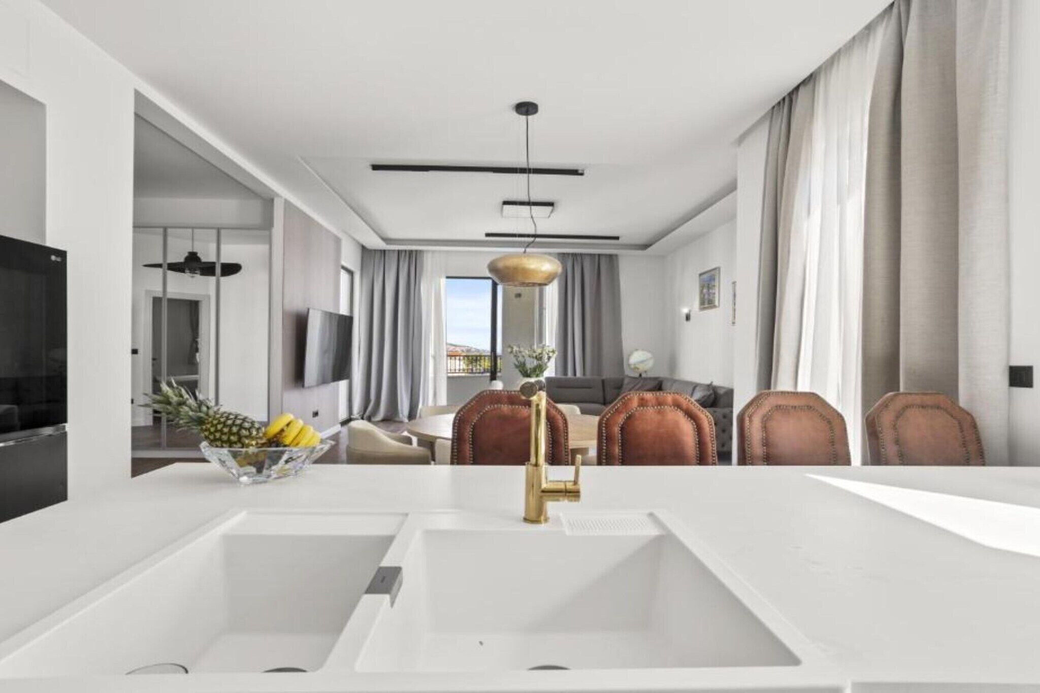 Una cocina moderna con encimera blanca, grifo dorado y frutero.