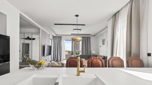 A modern kitchen with a white countertop, a gold faucet, and a fruit bowl. - Three-Bedroom Penthouse Apartment (Omis)