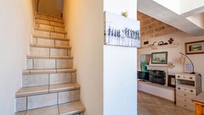 A staircase leading to a landing with a framed black and white photograph, a fireplace, and a shelf with decorative items. - Palazzo Bellavista by Rentbeat (Ostuni)