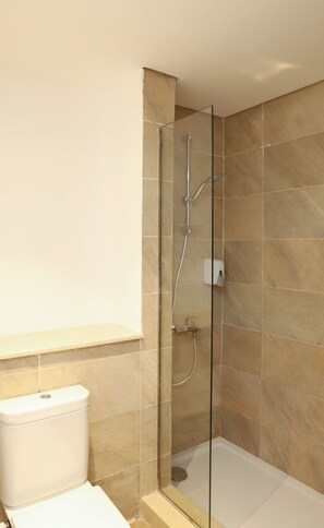 A modern bathroom with a glass-enclosed shower, beige tiles, and a white toilet. - Prime Holidays Marassi (El Alamein)