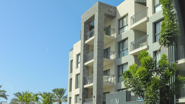 Un hôtel à plusieurs étages, doté de balcons, d’une enseigne indiquant « 11DM » et d’un jardin aménagé.