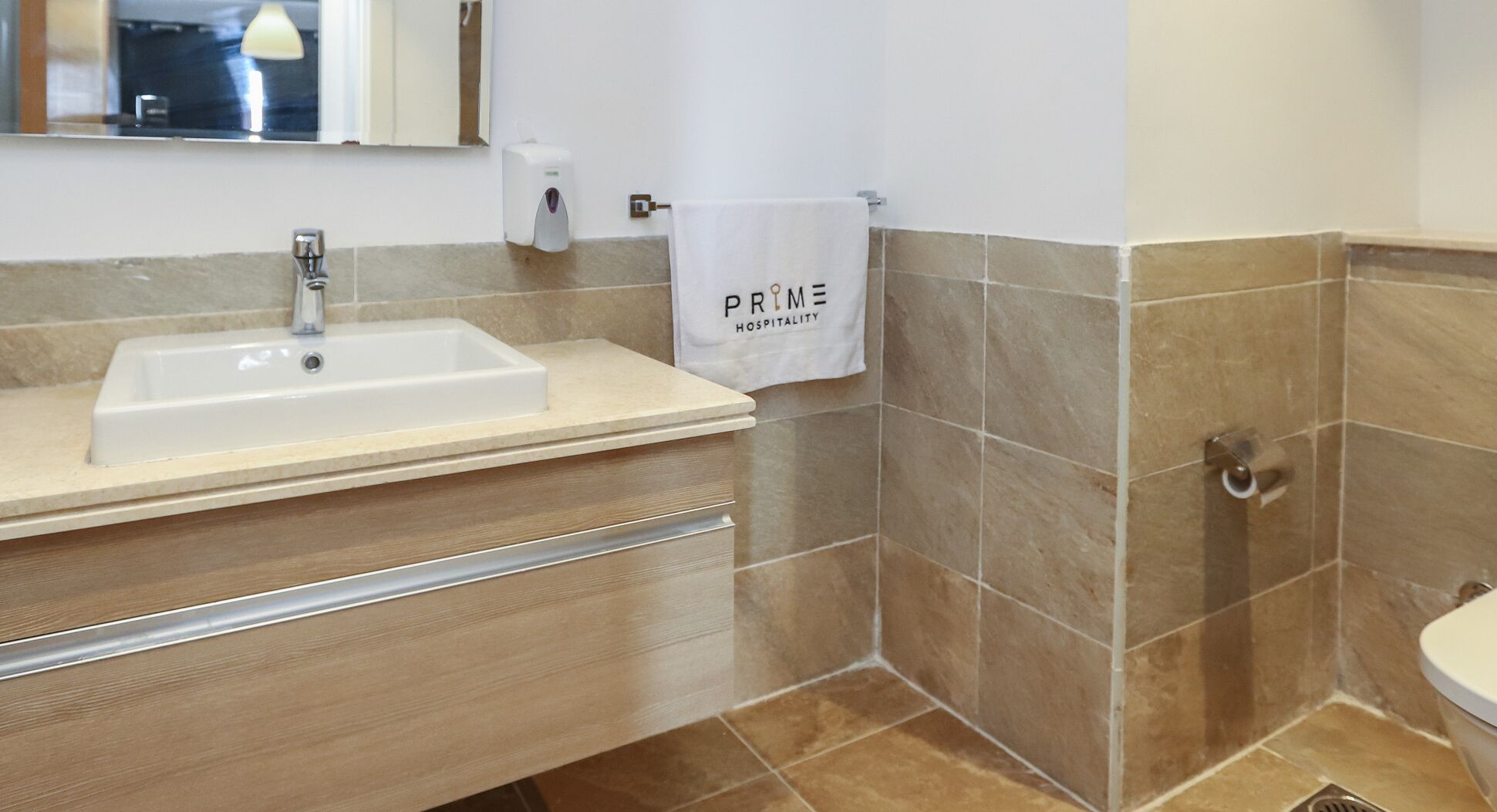 A bathroom with a sink, a towel hanging on a rack, and a toilet.