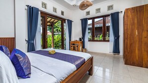 A bedroom with a bed, wooden headboard, and a small wooden table with a kettle. - Pondok Loris (Ubud)